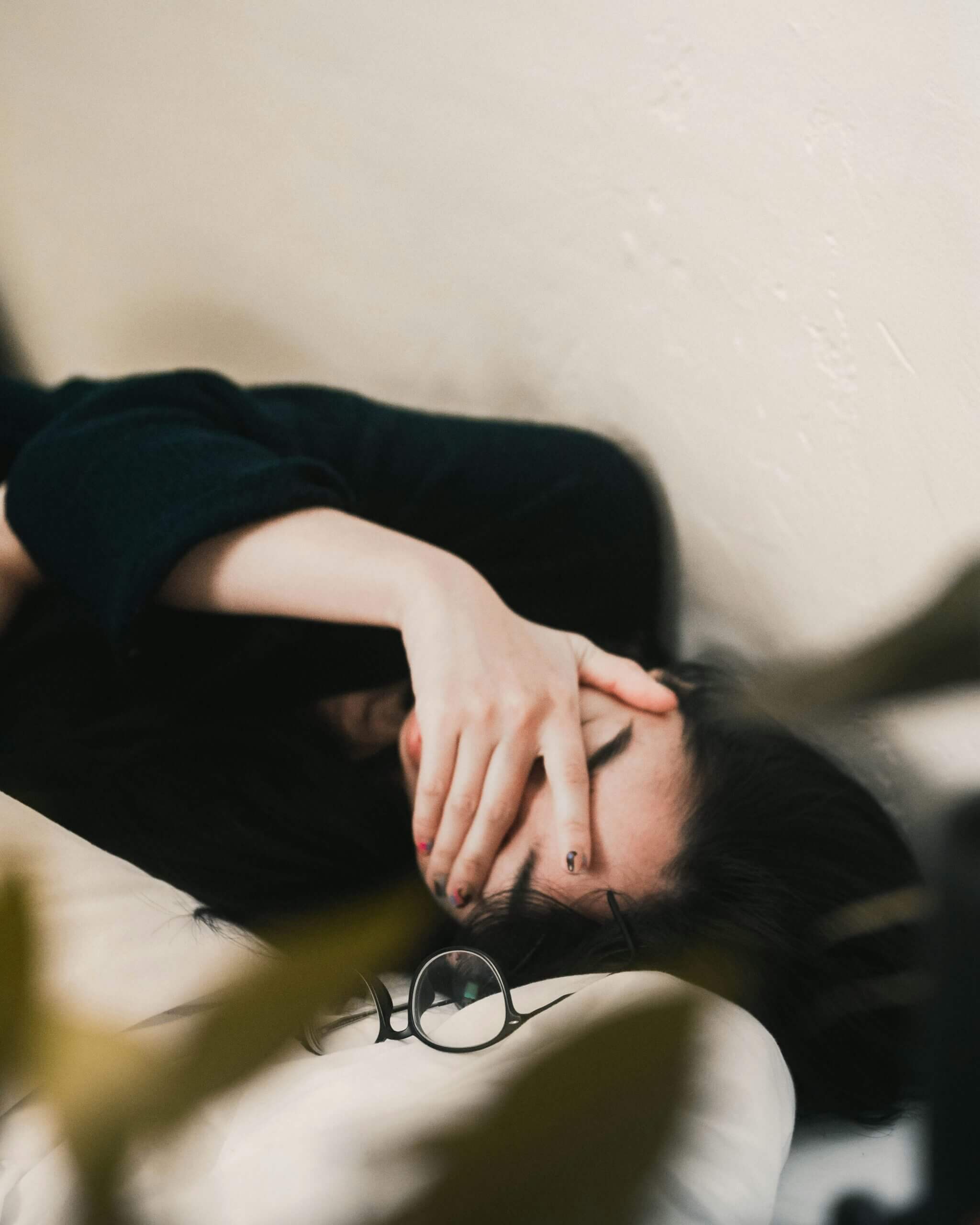 Woman lying down with hands covering her face, symbolising emotional burnout and ADHD exhaustion
