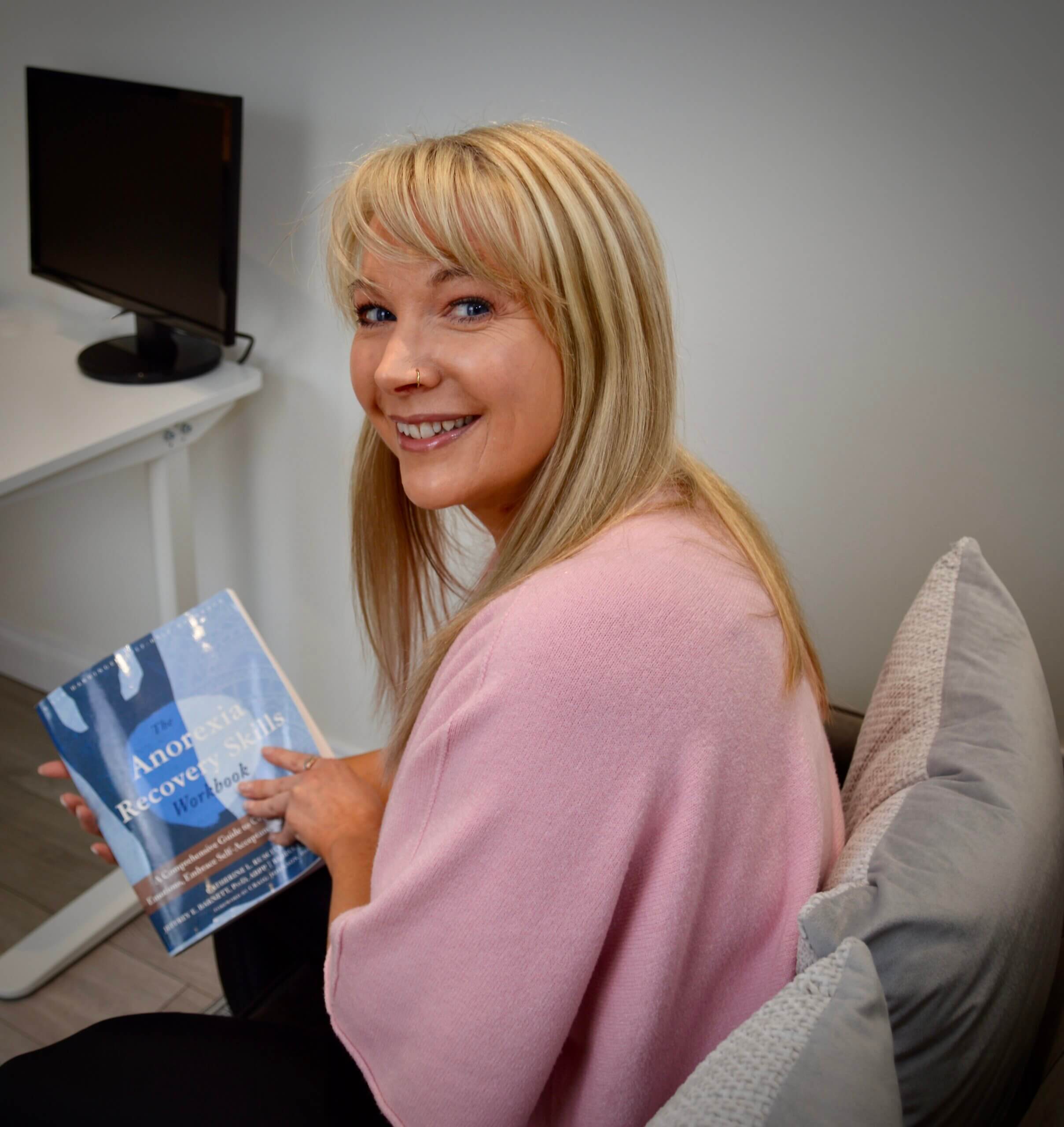 Becky Stone, trauma-informed eating disorder therapist in Canterbury, holding an eating disorder recovery workbook during an online therapy session, supporting adults and teenagers across the UK with anorexia, bulimia, binge eating disorder, ARFID and body image concerns.