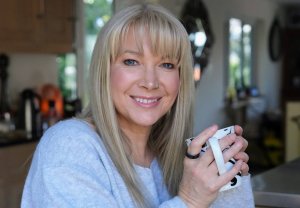 Becky Stone – Online Counsellor in Canterbury Becky Stone, online counsellor in Canterbury, smiling while holding a mug during a professional portrait.