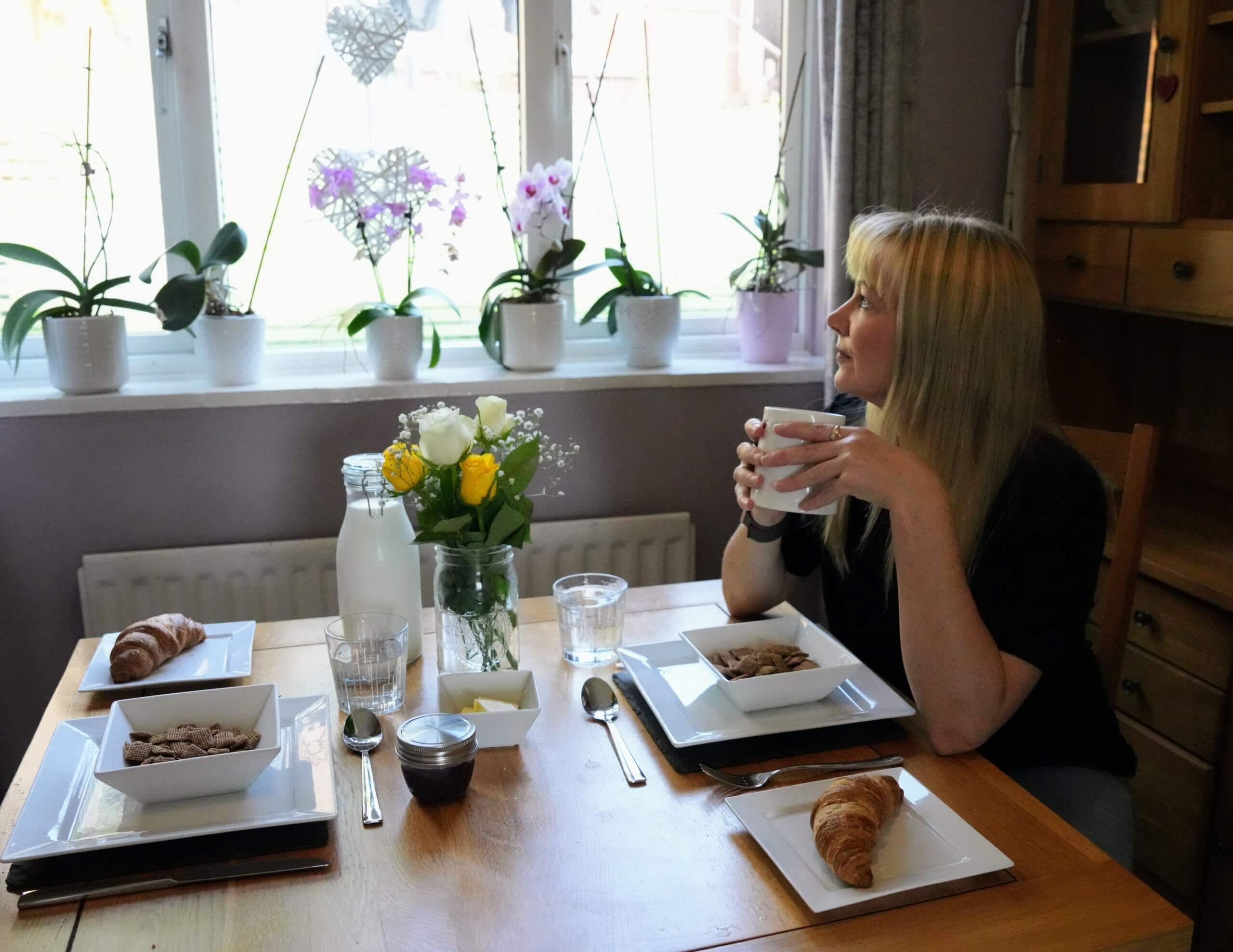 Becky Stone enjoying a cup of tea at a breakfast table, reflecting the warm and welcoming approach to online eating disorder therapy in the UK.